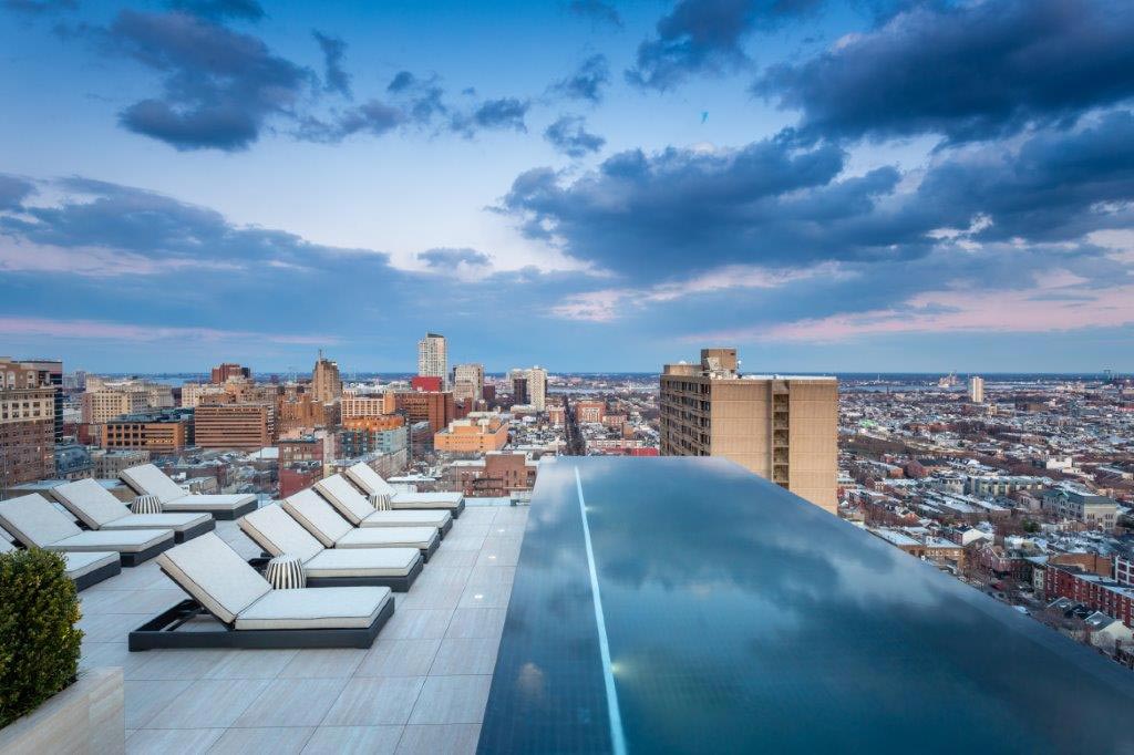 Stainless steel tiled roof top pool with four sided infinity edge, interior descending stairway, LED lighting  and bench seating. 156