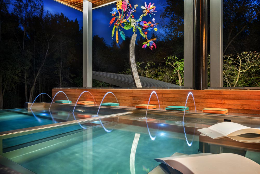 Custom stainless steel pool with glass window separating the spa.  Pool is designed with bench seating, sun shelf, descending stairway, laminar jets and automatic cover.