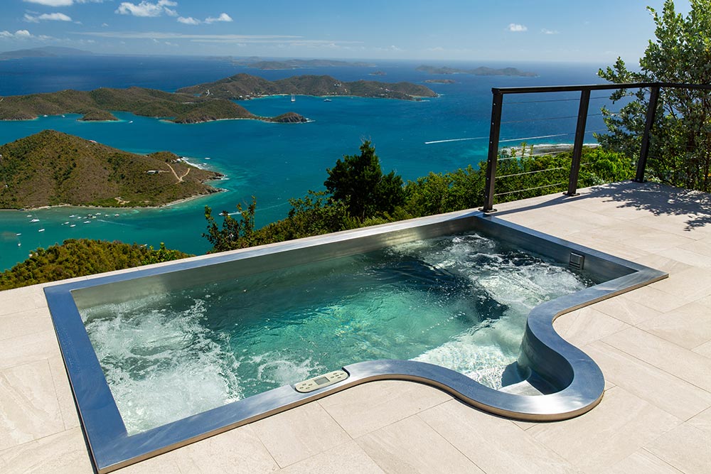 Custom stainless steel rooftop spa with LED lighting, two loungers, bench seating and interior descending stairway. 