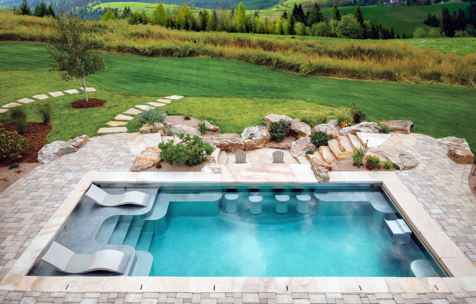 Stainless steel pool with sun shelf, bench seating on side walls of pool, swim up bar, swim spa system, laminar jets, and automatic cover. 193”x402”x69”