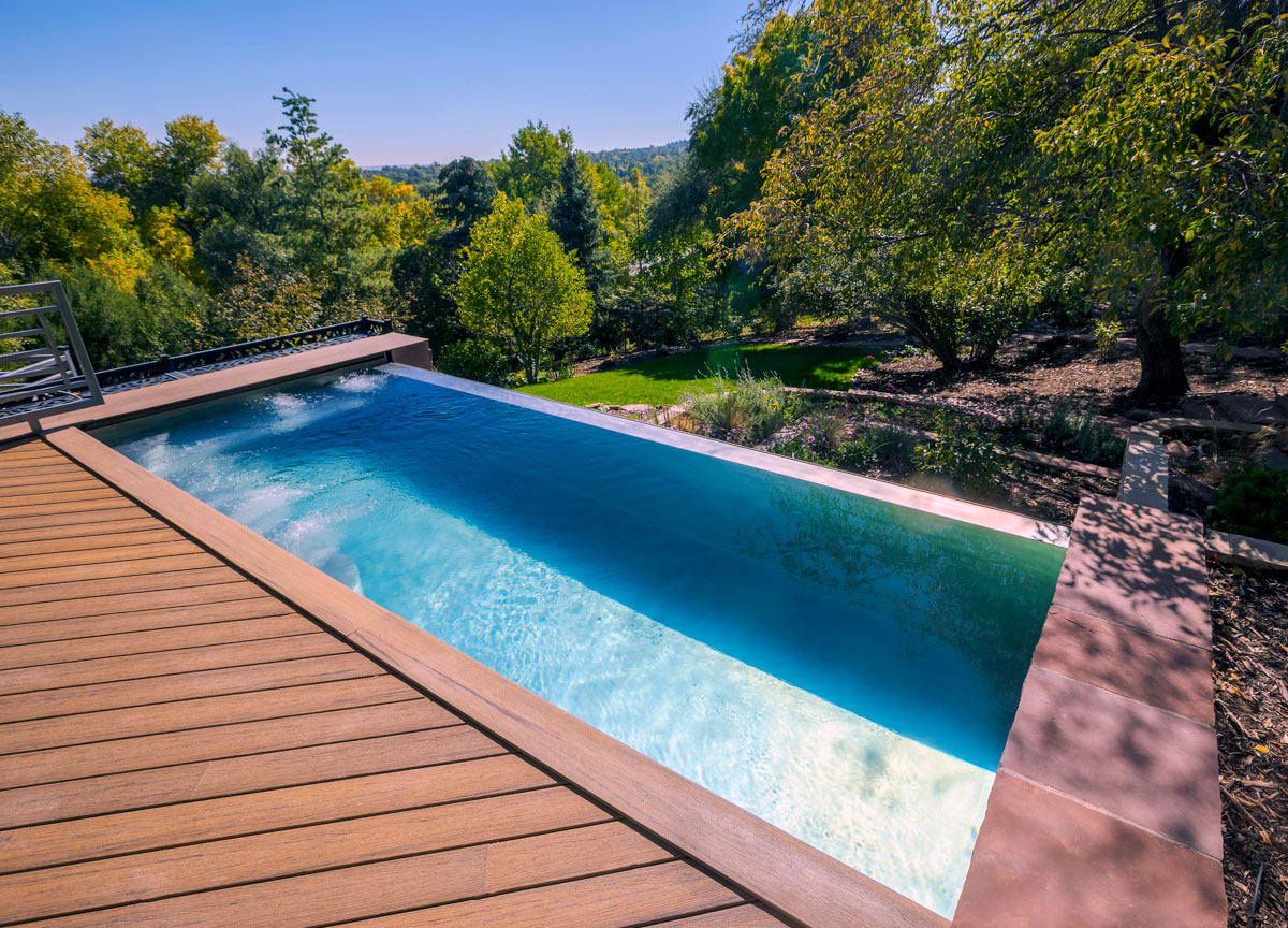 Stainless steel pool with bench seating and wall jets at far end, interior stairway, LED lighting, automatic cover and front infinity edge water feature.  128”x 277”x 58”