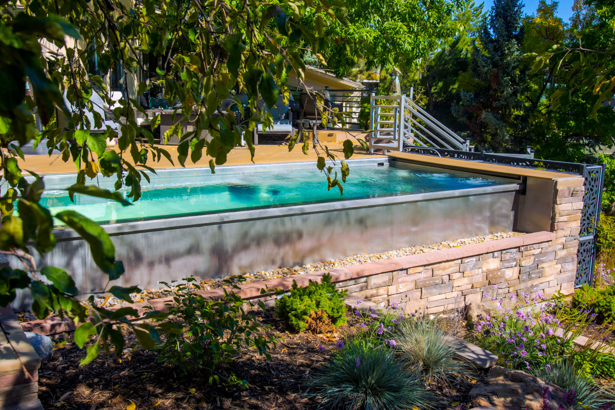 Stainless steel pool with bench seating and wall jets at far end, interior stairway, LED lighting, automatic cover and front infinity edge water feature.  128”x 277”x 58”
